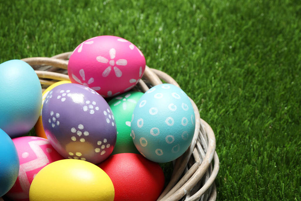 Colorful Easter eggs in decorative nest on green grass, closeup - Φωτογραφία, εικόνα