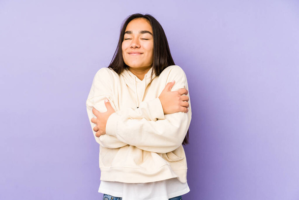 Jeune femme isolée sur un fond violet câlins, souriant insouciant et heureux
. - Photo, image