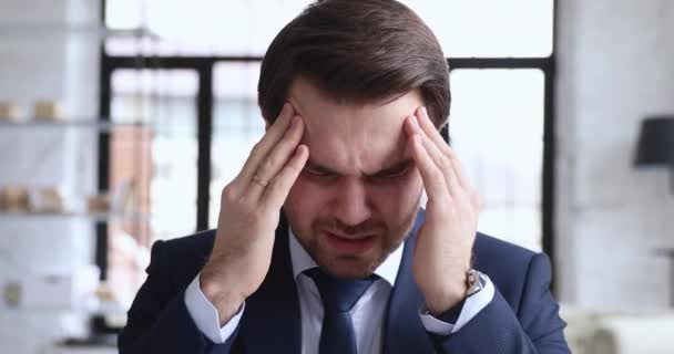 Stressed businessman wearing suit massaging temples suffering from migraine - Záběry, video