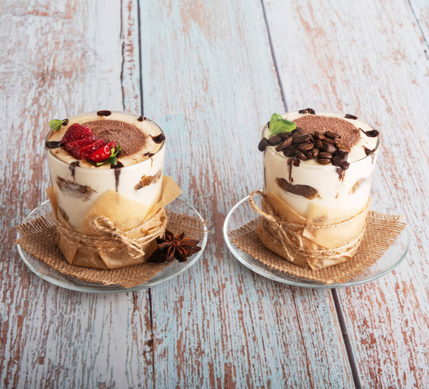 tiramisu in a glass with berries, mint and coffee beans on a light wooden background - Photo, Image
