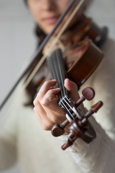 Estudiante joven practica violín en casa, vista frontal con la cara borrosa. Imagen vertical
 - Foto, imagen