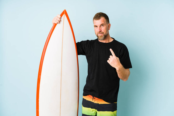 Surfen człowiek odizolowany na niebieskim tle wskazując palcem na ciebie, jakby zapraszając zbliżyć. - Zdjęcie, obraz