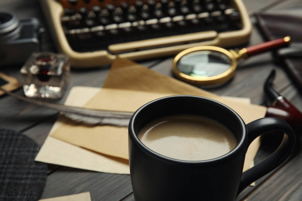 Composition with vintage detective items on grey wooden table, focus on cup of coffee - Фото, изображение