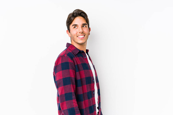 Young caucasian man posing in a pink background isolated looks aside smiling, cheerful and pleasant. - Photo, Image