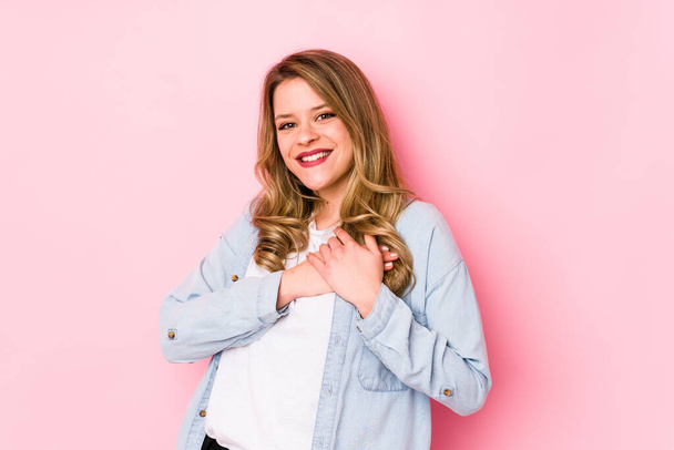Young caucasian woman isolated on pink background has friendly expression, pressing palm to chest. Love concept. - Photo, Image