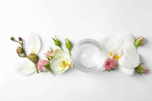 Composition with cosmetic gel and beautiful flowers on white background, top view - Foto, afbeelding