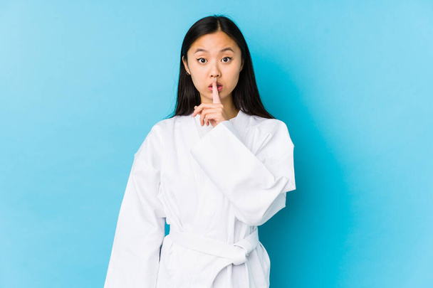 Jonge Chinese vrouw oefenen karate geïsoleerd houden van een geheim of vragen om stilte. - Foto, afbeelding