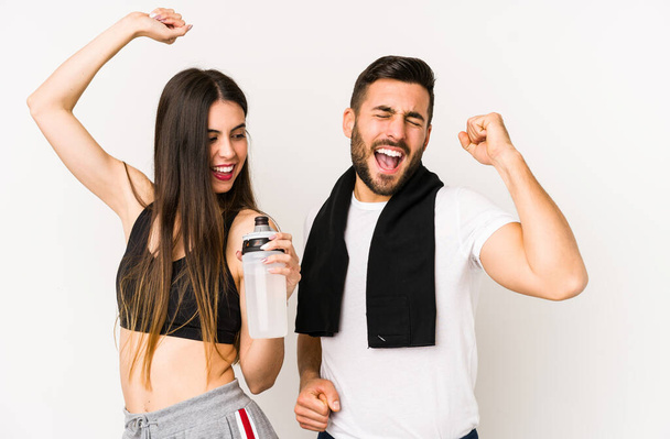 Young caucasian fitness couple isolated celebrating a special day, jumps and raise arms with energy. - Foto, Bild