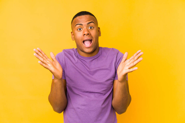 Young latin man isolated on yellow background celebrating a victory or success, he is surprised and shocked. - Foto, immagini