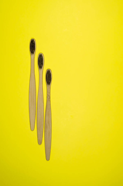 Bright bamboo eco toothbrushes on yellow background. - Photo, Image
