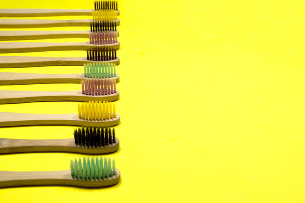 Bright bamboo eco toothbrushes on yellow background. Selective focus. - Zdjęcie, obraz