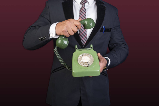 Бизнесмен, держащий стационарный телефон в руках, свяжитесь с нами
 - Фото, изображение