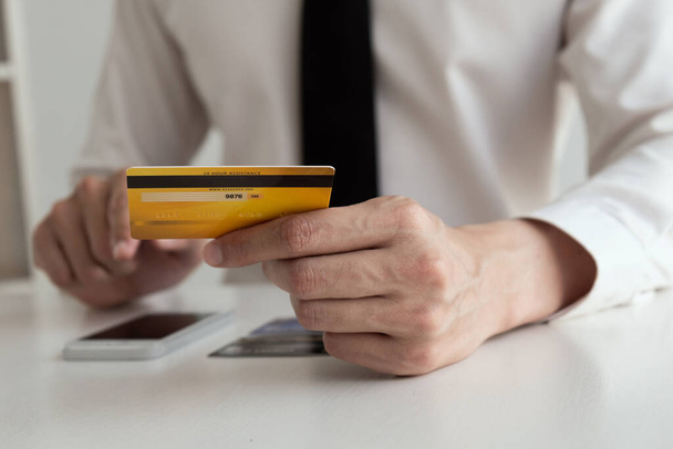 クレジットカードを持っている男の手と携帯電話を使用して、オンラインショッピングの概念. - 写真・画像
