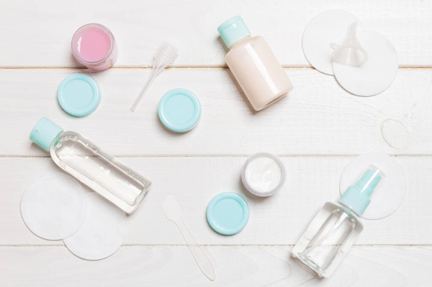 Top view of means for face care: bottles and jars of tonic, micellar cleansing water, cream, cotton pads on wooden background. Bodycare concept with empty cpace for your ideas. - Photo, Image