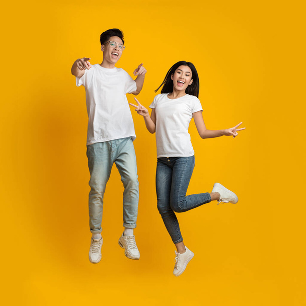 Unbekümmertes asiatisches Millennial-Paar springt glücklich in die Luft - Foto, Bild