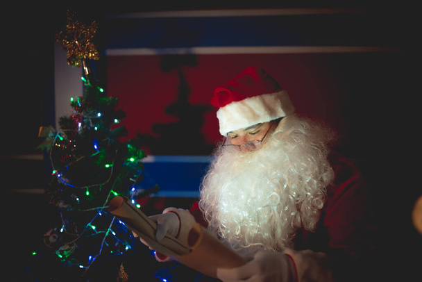 Portrait of santa clause read paper and checking list name for send gift to children - Foto, imagen