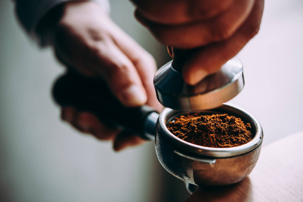 Barista presses ground coffee using tamper - Foto, Imagen