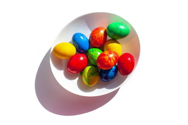 Colorful eggs on a white plate. Shadow. - Foto, afbeelding