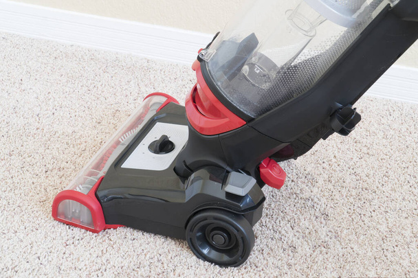 Vacumm cleaner is used to clean a carpet surface while doing houshold chores - Fotografie, Obrázek
