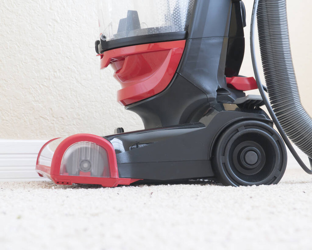 Vacumm cleaner is used to clean a carpet surface while doing houshold chores - Foto, imagen