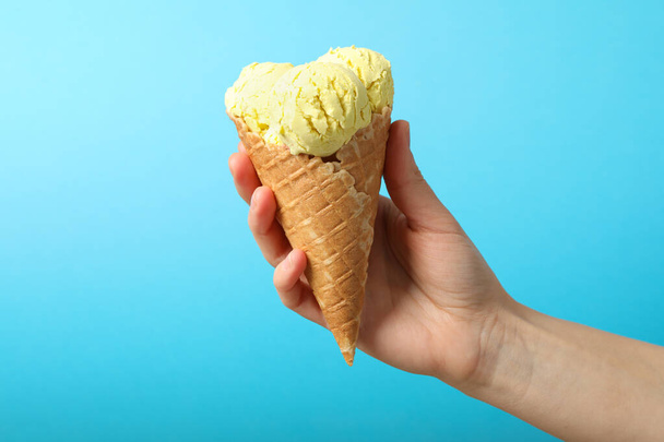 Žena ruka drží zmrzlinu na modrém pozadí, zblízka - Fotografie, Obrázek