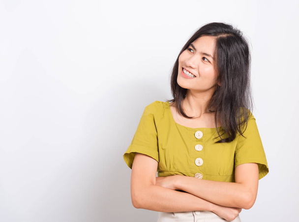 Portrait Asian beautiful young woman standing smile seeing white teeth, She crossed her arms and looking Above, shoot photo in studio on white background - 写真・画像