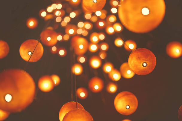 From below of hanging bright glowing red round lanterns on dark blurred background - Foto, Imagem