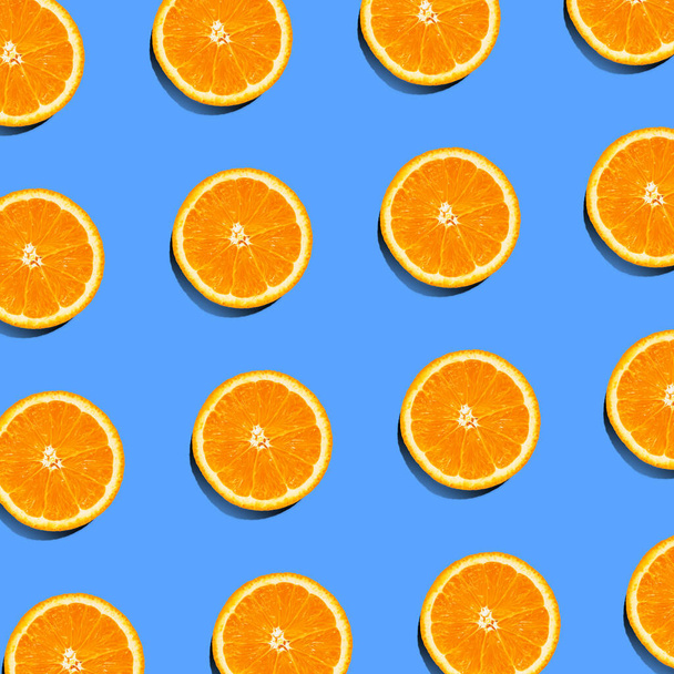 Tropisches Sommermuster frischer Orangenscheiben auf blauem Hintergrund. Draufsicht auf Querschnitt durch bunte Zitrusfrüchte. Kontrastierende flache Laienzusammensetzung - Foto, Bild
