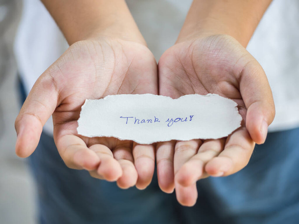El niño sosteniendo un pedazo de papel con la palabra Gracias en la sensación de la palma felicidad
. - Foto, imagen