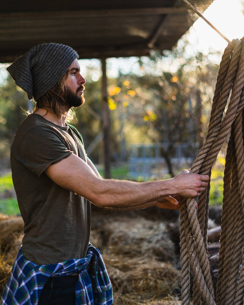Portrait of young man picking up rope on his farm - Photo, Image