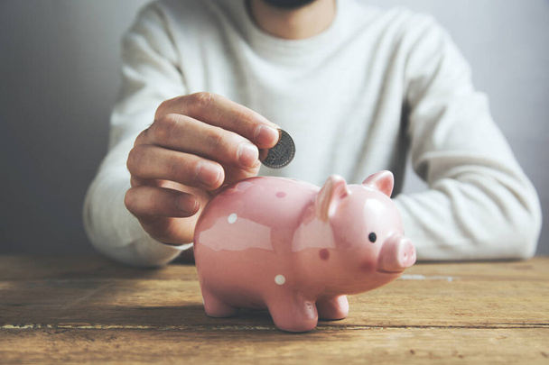 Man putting coin in piggy bank. Saving money concept - Foto, Bild