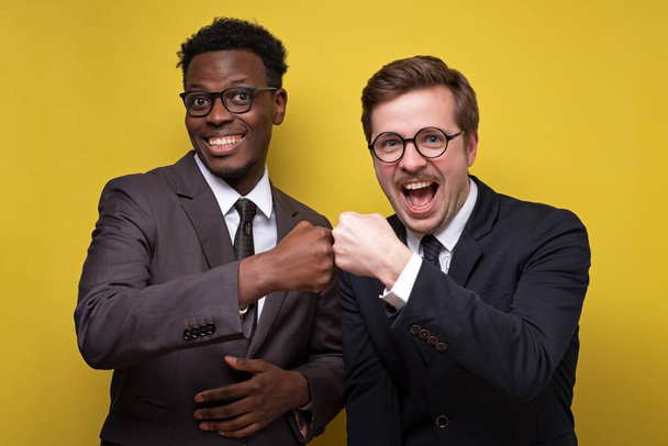 スーツを着た2人の自信のある男性アフリカ人と白人男性拳バンプを作ります - 写真・画像