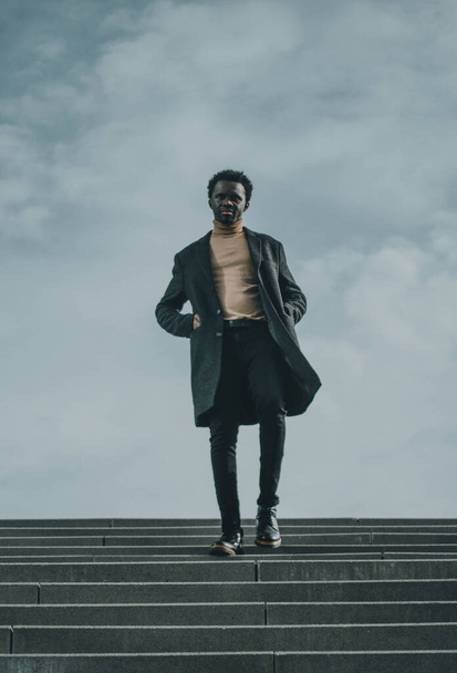 Negro joven hombre de negocios en las escaleras cerca del mar
 - Foto, imagen
