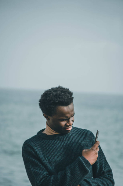 Egy fekete fiatalember portréja a strandon, amint fotózkodik. - Fotó, kép