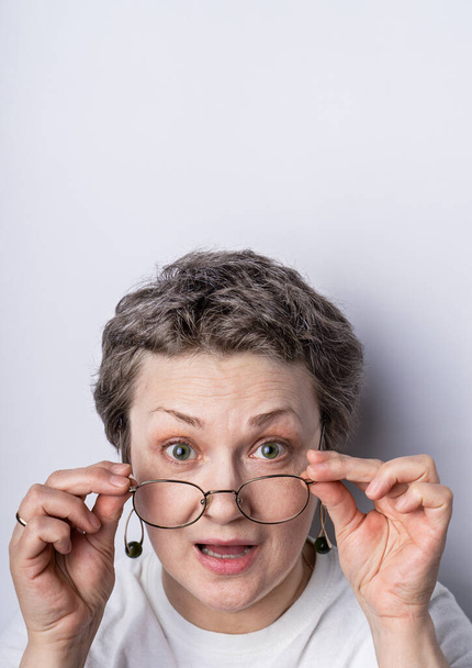 Imagen de una mujer de pelo gris de 40-50 años con gafas con expresión lúdica en la cara. Imagen vertical con espacio de copia
 - Foto, imagen