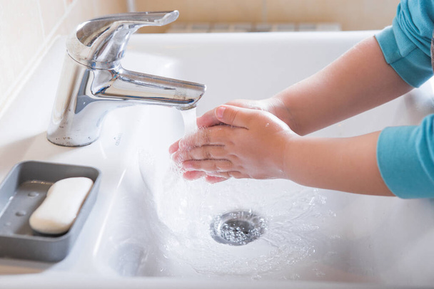 Lavarsi le mani bambino risciacquare sapone con acqua corrente al lavandino, Coronavirus prevenzione igiene delle mani. Protezione pandemica Covid-19 mediante bracci detergenti
 - Foto, immagini
