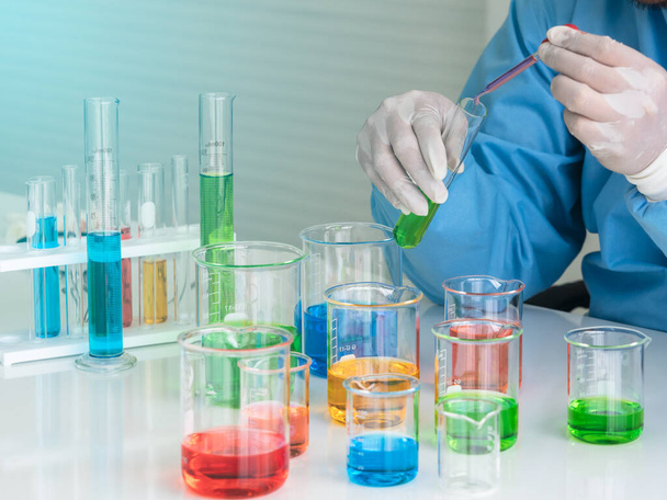 Scientist dropping red liquid into green fluid in the glass tube. Colorful liquid in the glass beaker and tube. Science, health , chemistry class and technology concept. - Foto, Bild