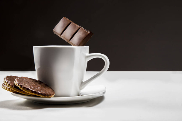 Kurabiyeli sıcak çikolata. Bir fincan ve uçan çikolata. Tatlı bir şey. Kahve ve tatlı.. - Fotoğraf, Görsel