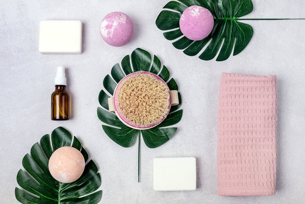 SPA Still Life Background Pink and Light Orange Bath Bombs Soaps Cosmetic Oil on Light Gray Background Washing Brush Pink Towel Spa Beauty Concept Top View Flat Lay Monstera Leaf - Fotografie, Obrázek
