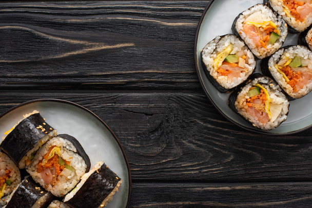 top view of plates with korean gimbap on wooden surface  - Foto, imagen