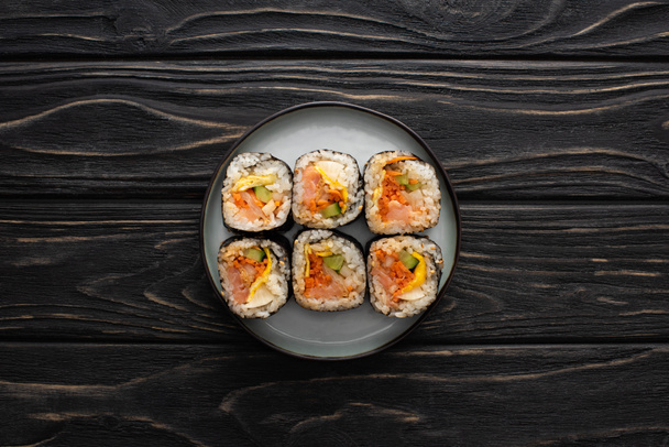 top view of plate with tasty gimbap on wooden surface  - Foto, afbeelding