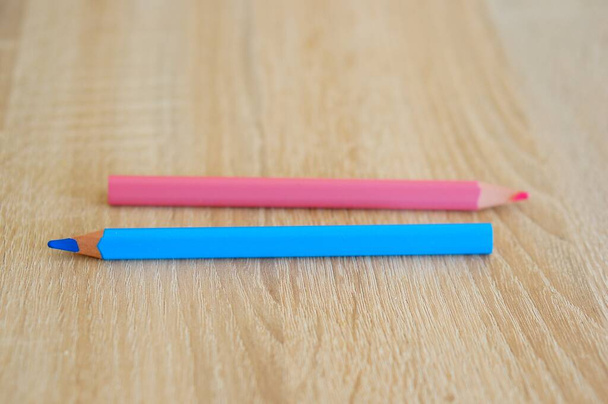 A closeup shot of two blue and pink drawing pencils on a wooden surface - Φωτογραφία, εικόνα