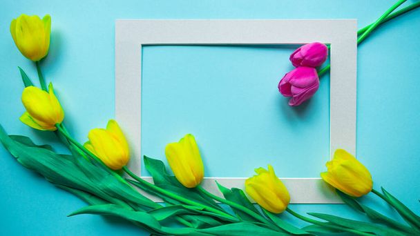 Feliz tarjeta de primavera. Tarjeta de felicitación creativa con el ramo de hermosas flores de tulipanes amarillo primavera sobre el fondo azul claro. Copia espacio, banner o plantilla. plano laico, naturaleza muerta, vista superior
. - Foto, imagen
