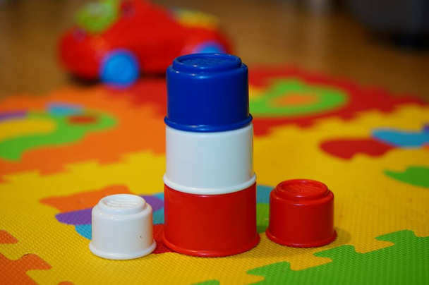A closeup shot of colorful toy cups on puzzle mat - Photo, image