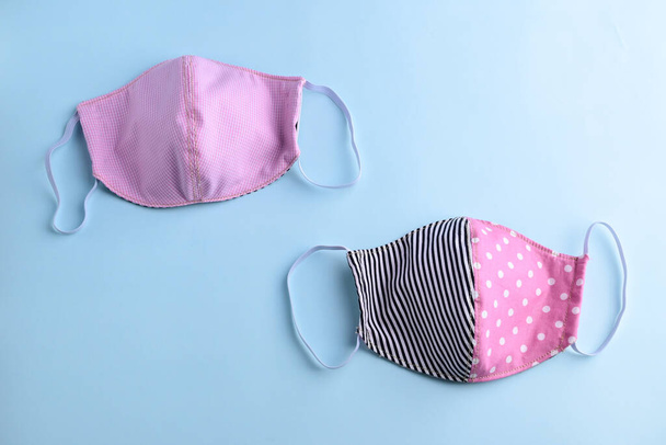 flat lay design of black and pink colorful fashion face mask handmade from fabric cloth on blue background - Foto, Bild