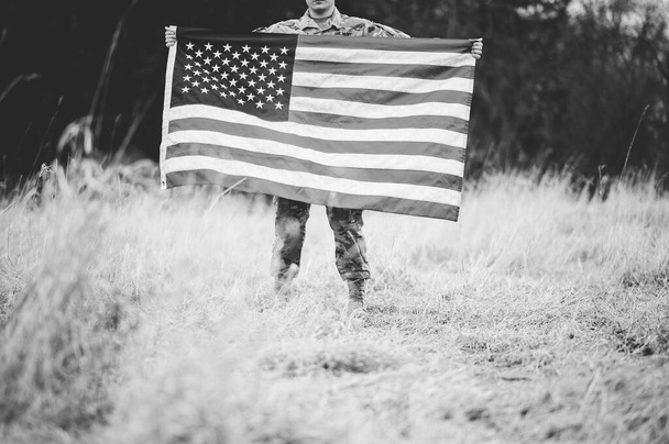 A shallow focus shot of an American soldier holding the American flag - Fotografie, Obrázek