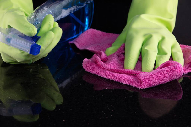 A maid with rubber gloves cleaning the table with a microfiber cleaning cloth and sterilizing spray bottle - Фото, зображення