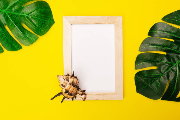 maquette tropicale avec cadre photo blanc et feuilles de palmier sur fond jaune coloré. Cadre photo avec place vide pour le texte ou la publicité avec coquillages sur fond jaune
. - Photo, image