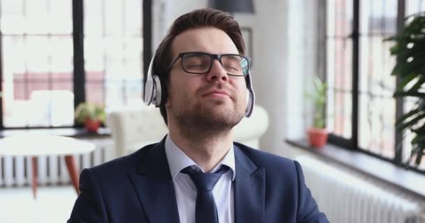 Happy calm professional businessman listening to music in office, closeup - Filmati, video