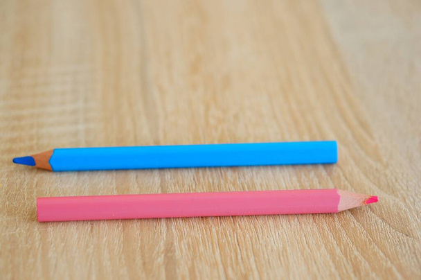 A closeup shot of two blue and pink drawing pencils on a wooden surface - Φωτογραφία, εικόνα